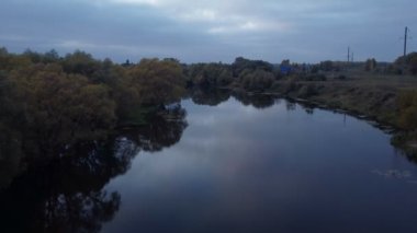 Kırsal bir bölgede kırsal bir nehrin üzerinde uçan bir dron fırtınadan önce kıyıda ağaçlar vardı..