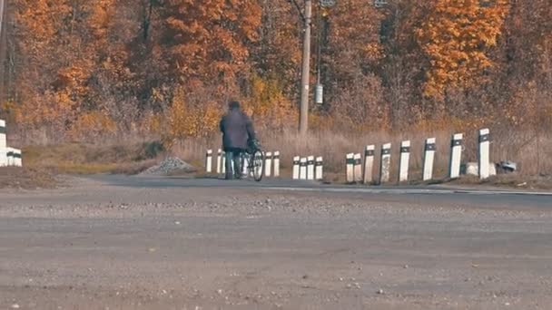 一个骑自行车的人在秋天泛黄的树木的衬托下穿过一个铁路交叉口 — 图库视频影像