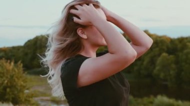 Uzun saçlı güzel bir kızın duygusal portresi sonbaharın başlarında gün batımında seçici bir odak noktasında doğanın arka planına karşı..