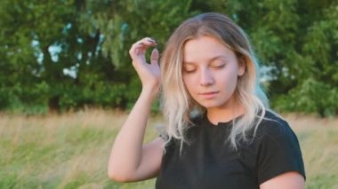 Saçlarına dokunan güzel bir kızın duygusal portresi sonbaharın başlarında gün batımında duygular ve seçici bir gülümseme ile doğanın arka planına dokunuyor..