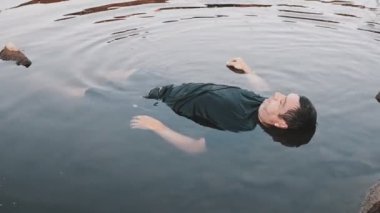 Bir adam boğuldu, suda öldü, yaşlanmış bir genç adam gölde yatıyor, kirli bir gölette bir ceset kararsız bir kamera hareketi renk düzeltmesi.