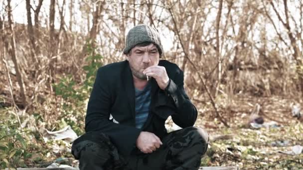 Ένας Άστεγος Πεινασμένος Άντρας Ντυμένος Ελαφρά Στο Δρόμο Καπέλο Καπνίζει — Αρχείο Βίντεο