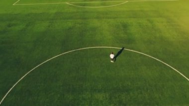 Genç bir kız, yeşil bir futbol sahasında bir hava aracıyla havaalanının tepesinden koşuyor..