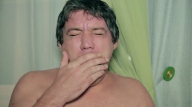 Çıplak gövdeli yetişkin bir adam ağzını esnemekten ve uyumak istemekten eliyle kapatır. Terbiye kavramı.