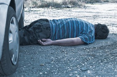 Bir araba kazasından sonra yolda ölü bir adam yatıyor.