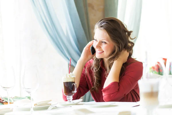 A woman in restaurant is talking to mobile phone — Stock Photo, Image