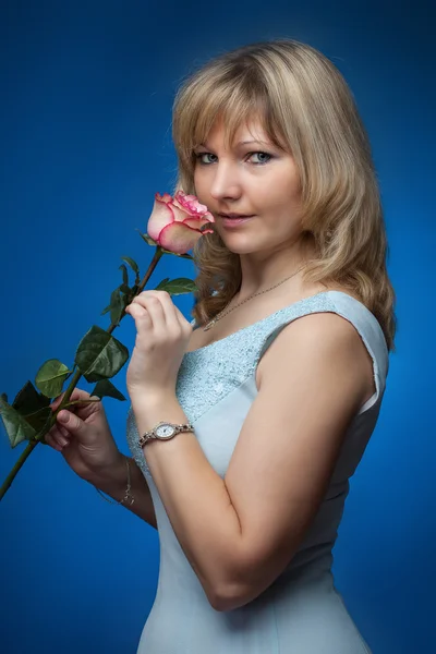 Mooie lachende vrouw met roos in een studio — Stockfoto