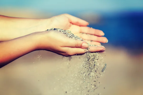 Een vrouw met zand door middel van haar handen van vallen — Stockfoto