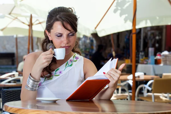 Jonge brunette vrouw drinkt koffie in een café — Stockfoto