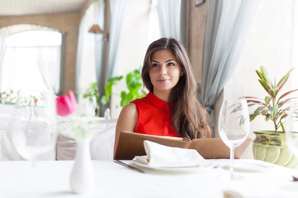 Uma mulher em um restaurante com o menu nas mãos — Fotografia de Stock