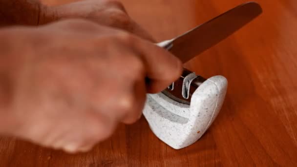 Mann schärft Küchenmesser manuell im Schleifer. — Stockvideo