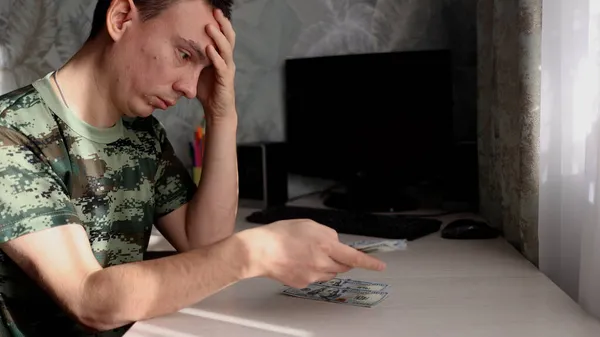 Uomo depresso contando banconote in dollari e sentendosi preoccupato per il problema finanziario. — Foto Stock