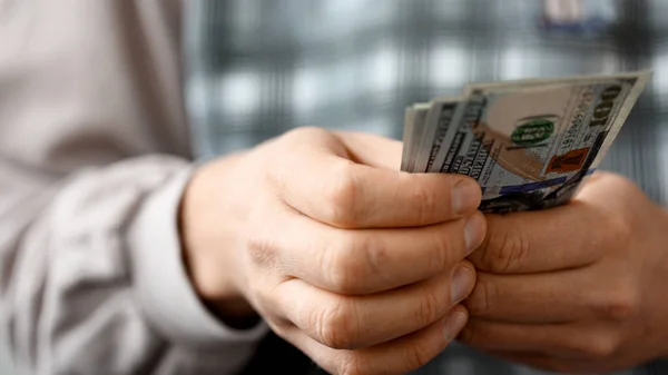 Hands of man in blue t-shirt counting US Dollar bills — Stock Photo, Image