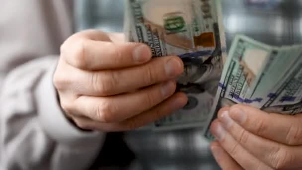 Руки человека в синей футболке, считая купюры в долларах США — стоковое видео