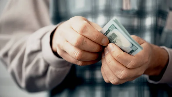 Hands of man in blue t-shirt counting US Dollar bills — Stock Photo, Image