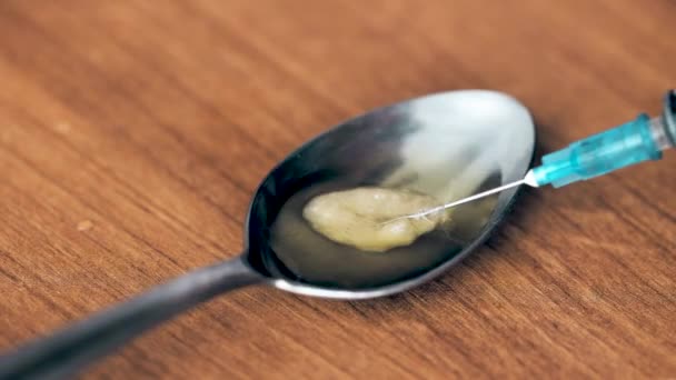 Close-up da agulha da seringa extraindo heroína de uma colher — Vídeo de Stock