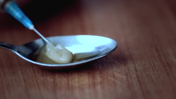 Nahaufnahme einer Spritzennadel, die Heroin aus einem Löffel extrahiert — Stockvideo