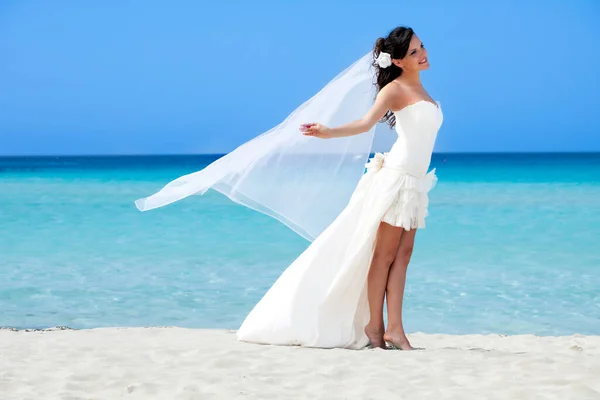 一位穿着白色婚纱的年轻新娘在海滩上散步 — 图库照片