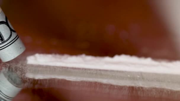 Кокаиновый наркоман нюхает кокаин со свернутой купюрой в долларах США. — стоковое видео
