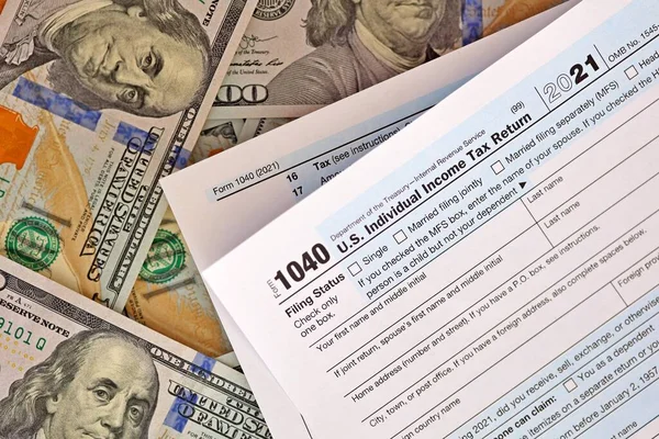 100 dolarlık banknotlarla birlikte ABD 1040 bireysel gelir vergi iade formu. — Stok fotoğraf