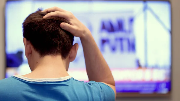 Man watching TV news sitting on sofa in living room. — Stock Photo, Image