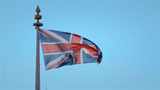 Szél-rongyos Brit Unió Jack zászló repül a kék ég — Stock videók