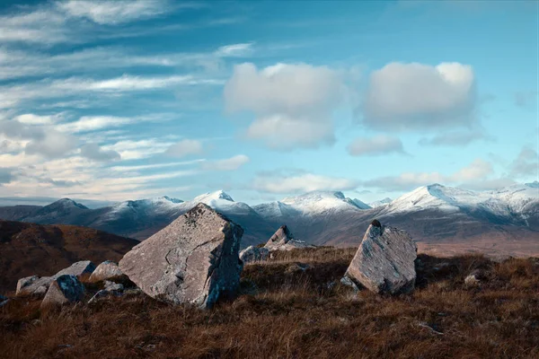 Stora stenar i förgrunden och snöiga bergstoppar — Stockfoto