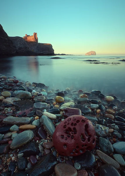 Gün batımında deniz koyunun kıyısındaki bir uçurumda duran eski bir şatonun kalıntıları.
