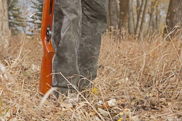 Gun stock at hunters feet in the forest — Stock Photo, Image