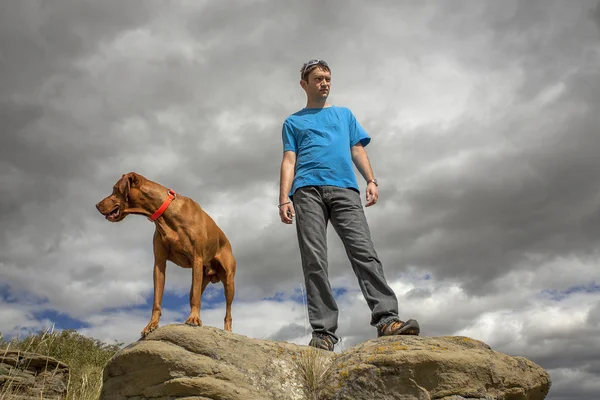 Man and dog on top of cliff — Stock Photo, Image