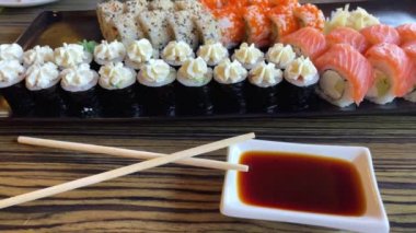 Hazır Japon suşi ruloları Hosomaki, uramaki, börek, zencefil, soya sosu ve suşi çubukları bir restorandaki masada.