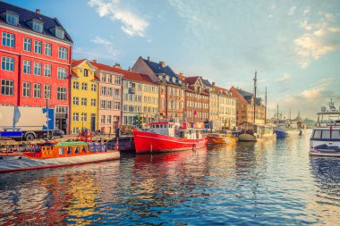 Nyhavn Kanalı 'ndaki eski çok renkli evlerin yakınında eski kırmızı ve beyaz bir balıkçı teknesi ve yatlar arasında duruyor. Kopenhag, Danimarka