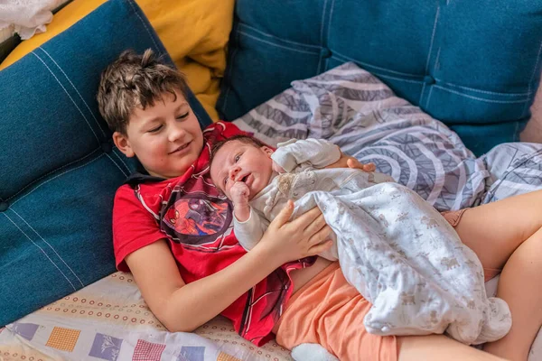 Teenage Boy Lies Couch Holding His Younger Newborn Brother His Stockfoto