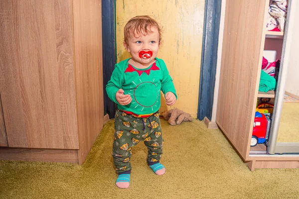 Komik, kızıl saçlı, erkek bebek odasında duruyor.