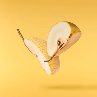Fresh yellow ripe raw pear falling in the air isolated on yellow background. Food zero gravity conception. High resolution image.