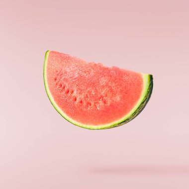 Fresh raw watermelon falling in the air isolated on pink background. Food levitation or zero gravity conception. High resolution image.