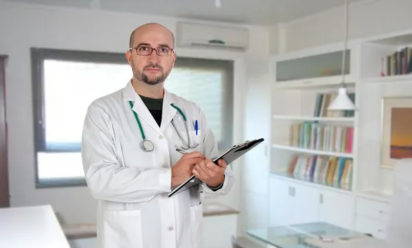 Doctor with clipboard and paperwork in his office — Stock Photo, Image