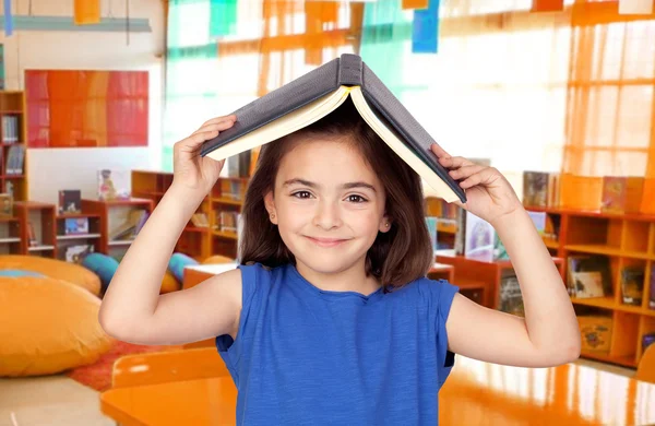 Bruna bambina con un libro in testa — Foto Stock