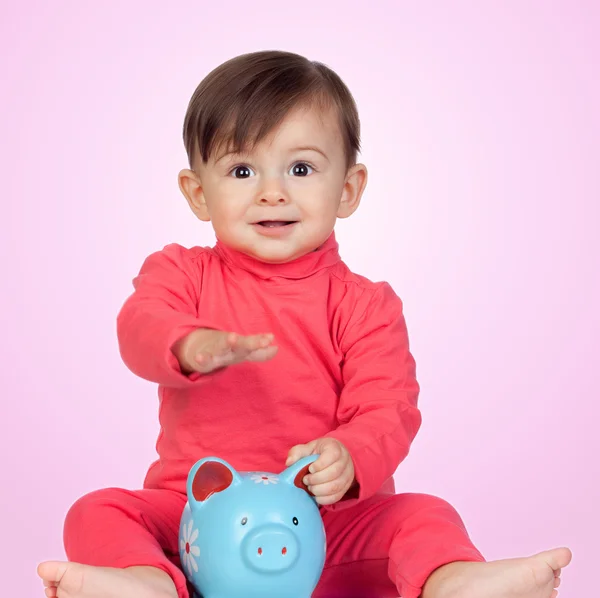 Adorable baby girl sitting with a blue piggy-bank — Stock Photo, Image
