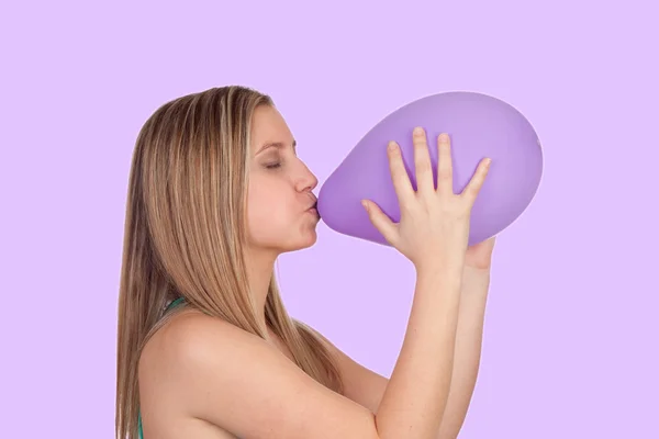 Menina loira atraente inchando um balão roxo — Fotografia de Stock