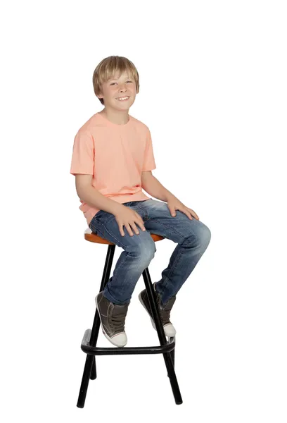 Lachende jongen met oranje t-shirt zitten op een kruk — Stockfoto