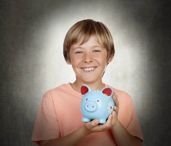 Sorrindo menino segurando um porquinho-banco azul — Fotografia de Stock