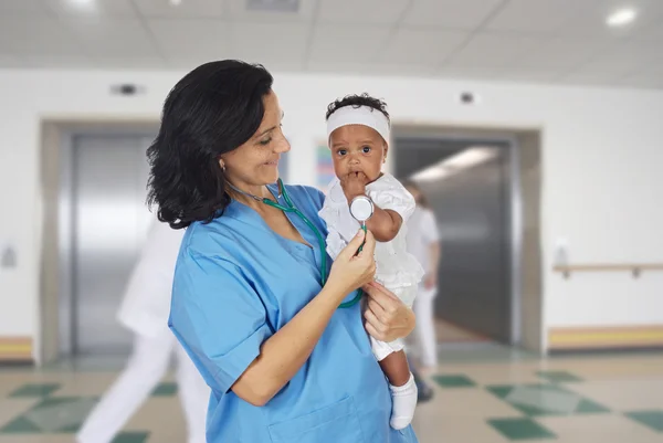 Brunett barnläkare på sjukhuset med en baby — Stockfoto