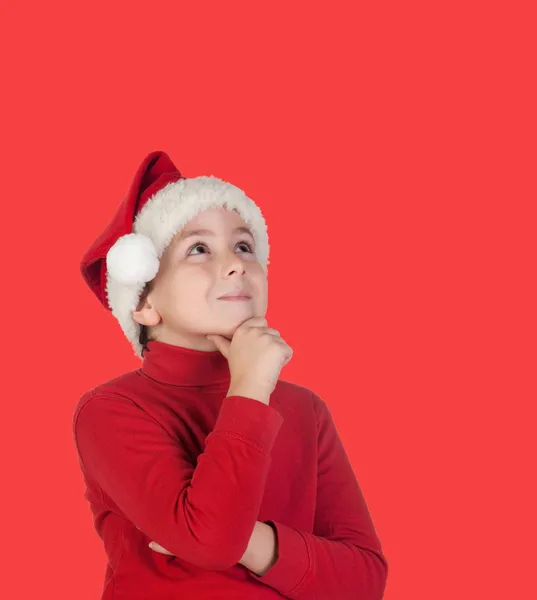 Pensive child with blond hair and Christmas hat — Stock Photo, Image