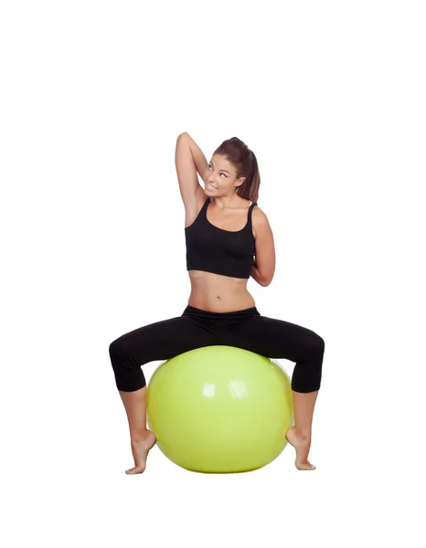 Jeune belle femme assise sur une balle de gymnastique étirant le bras — Photo