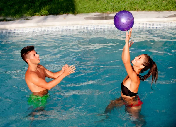 Lyckliga par avkopplande i poolen leker med en boll — Stockfoto