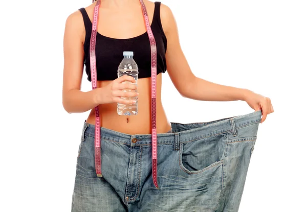 Mujer delgada de vuelta con pantalones enormes y botella de agua — Foto de Stock