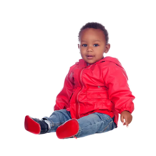 Adorável bebê africano sentado no chão com capa de chuva vermelha — Fotografia de Stock
