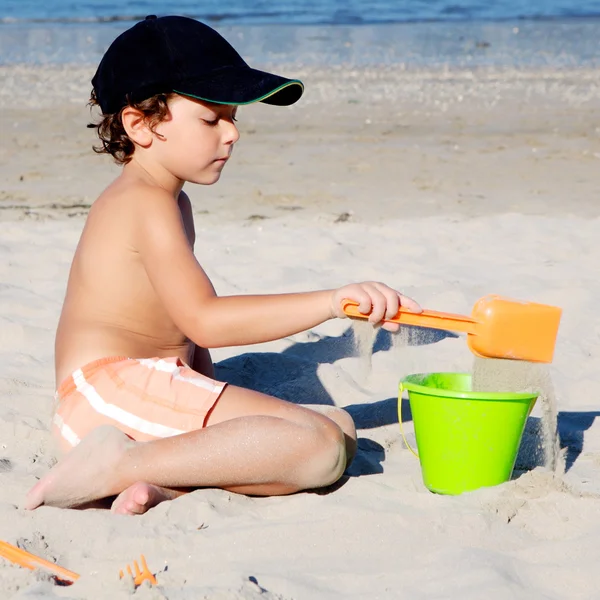 Liten pojke med hatt spela på stranden — Stockfoto