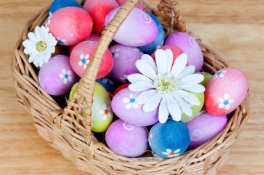 Easter eggs decorated with daisies tucked in a basket clipart